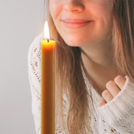 Woman is smelling the pleasent scent of beeswax candle