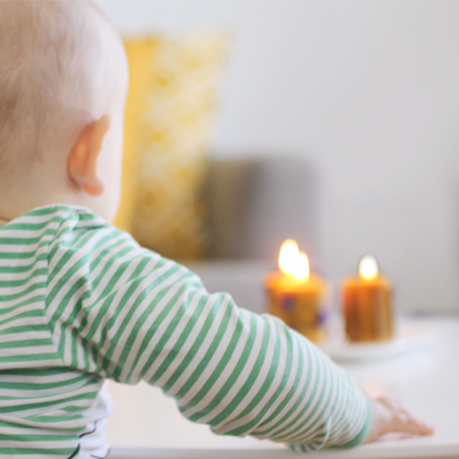 A baby is looking at the candle light